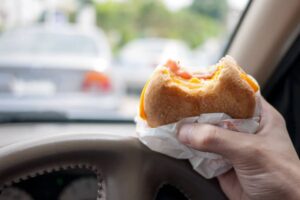 Persona che tiene in mano un panino in macchina