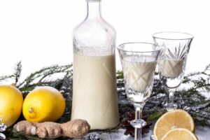 bottiglia e due bicchieri con la crema al limoncello, limoni sul tavolo
