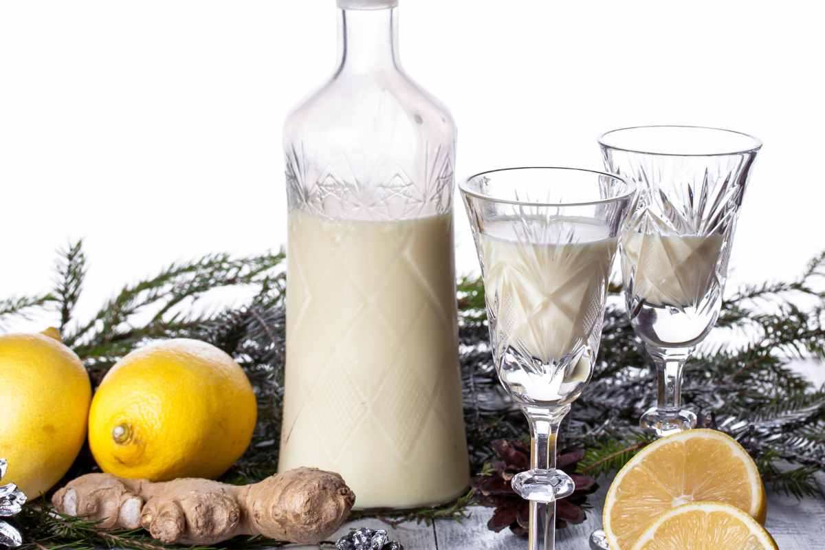 bottiglia e due bicchieri con la crema al limoncello, limoni sul tavolo