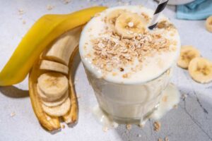 Bicchiere con liquido alla banana, mandorle e rotolini di banana
