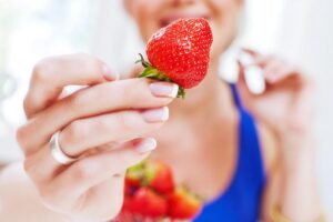 Donna che mostra una fragola matura