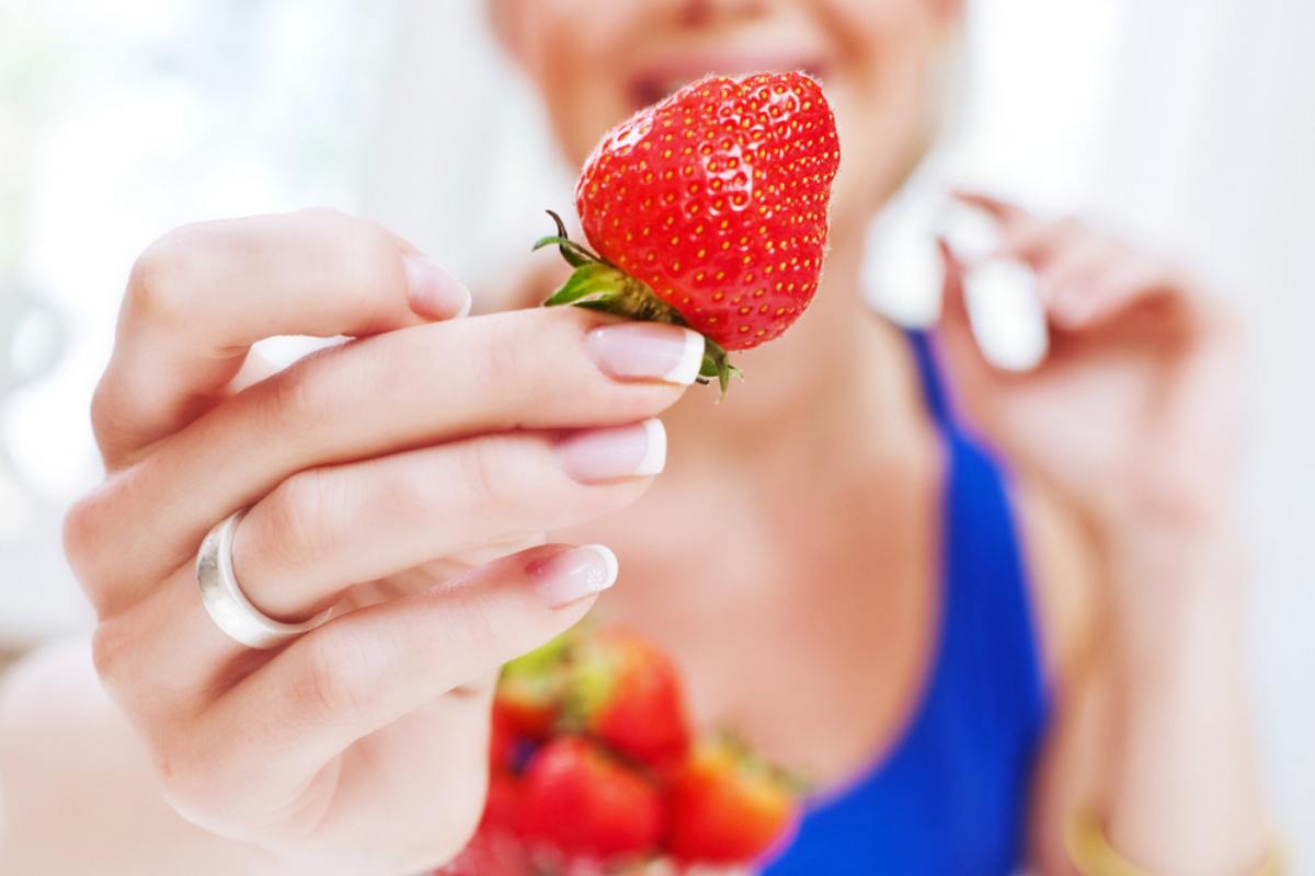 Donna che mostra una fragola matura