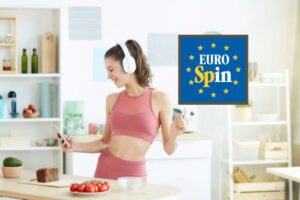 donna con le cuffie in cucina che guarda il cellulare e logo eurospin