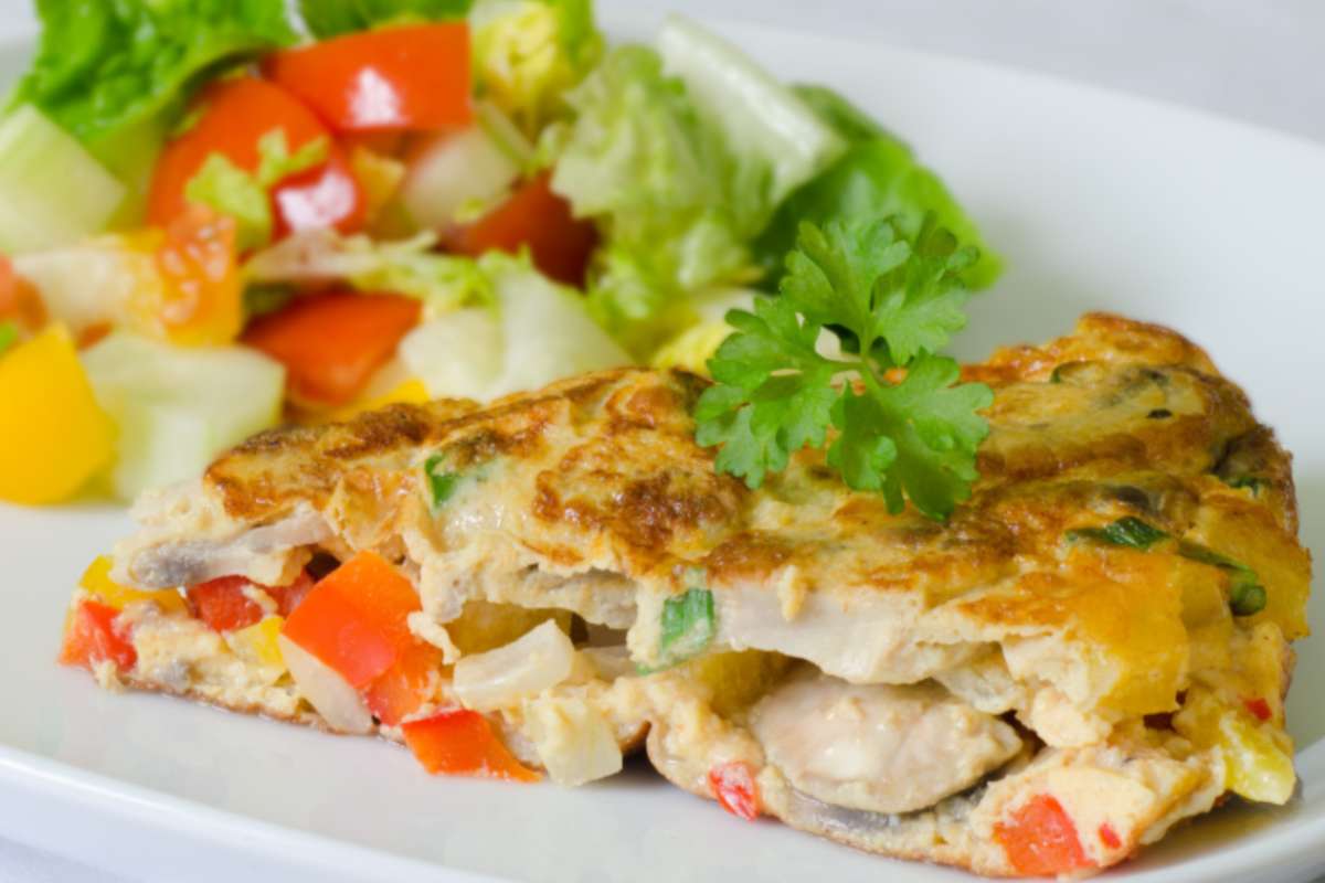 fetta di farifrittata di verdure su un piatto con accanto dell'insalata
