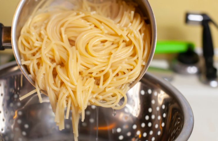 persona che scola gli spaghetti