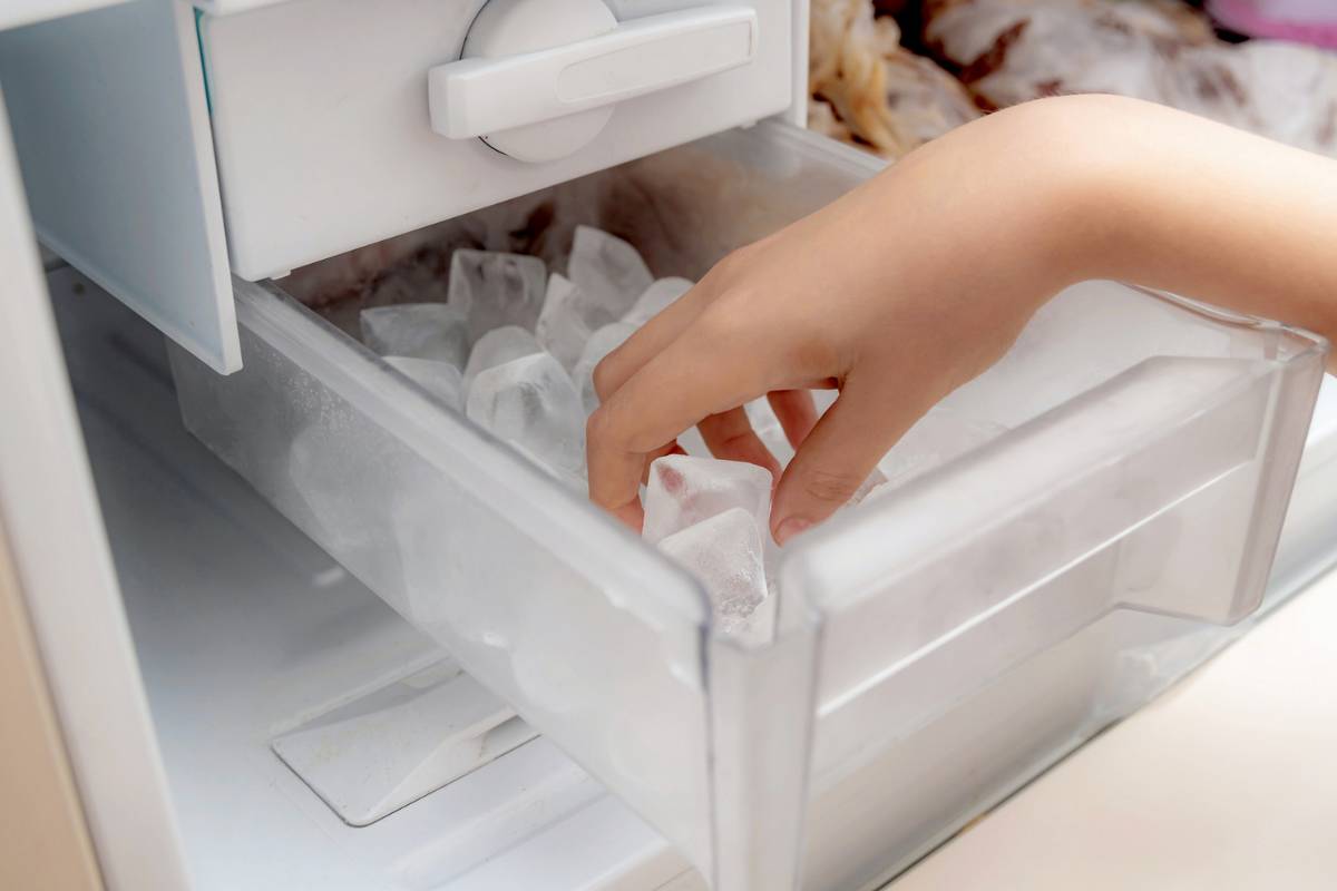 Persona che prende cubetti di ghiaccio da freezer