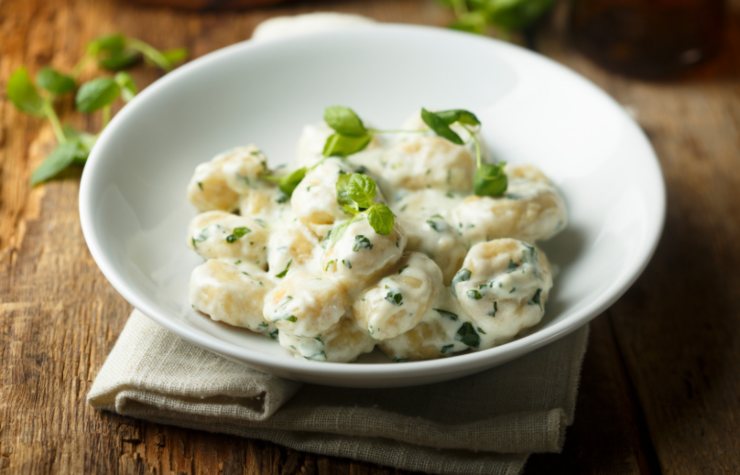 piatto di gnocchi in bianco cremosi con sopra del basilico tritato