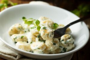 gnocchi conditi con una salsa bianca cremosa e del basilico tritato
