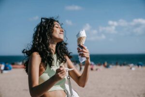 ragazza che mangia un cono gelato in spiaggia