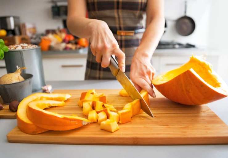 donna che taglia la zucca su tagliere