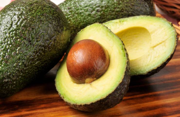 avocado tagliato a metà e dietro altri avocado