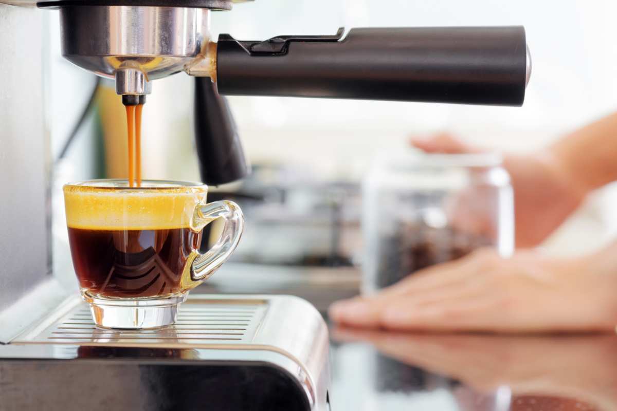 Tazzina piena sotto macchinetta del caffè