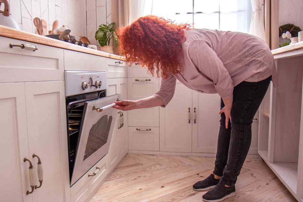 Donna in cucina che apre il forno