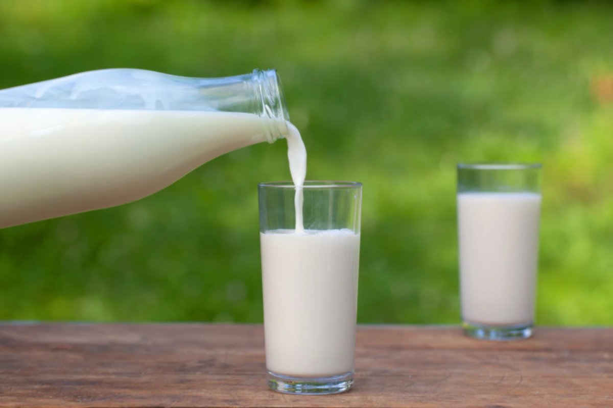 persona che versa il latte in un bicchiere