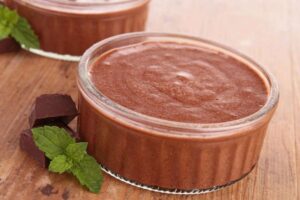 mousse al cioccolato dentro ad un bicchierino di vetro e accanto delle foglie di menta