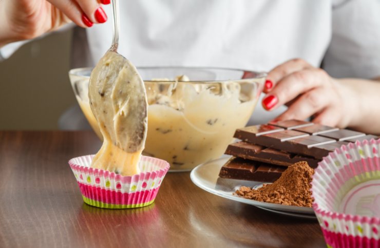 donna che mette l'impasto dei muffin nei pirottini 
