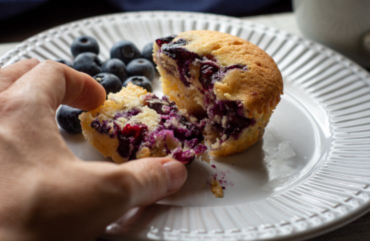 persona che prende un pezzo di muffin ai mirtilli