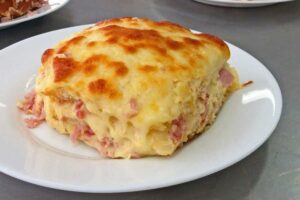 Porzione di parmigiana con prosciutto cotto e formaggio