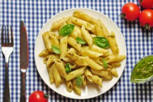 penne al pesto in un piatto su tovalgia a scacchi