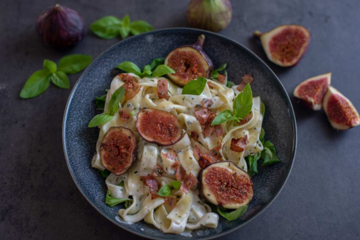 tagliatelle cremose con sopra dei fichi e delle foglie di basilico