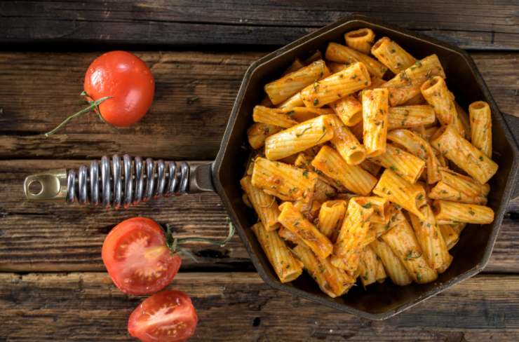 rigoni al pomodoro dentro ad una padella e accanto dei pomodori