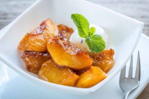 coppetta con pesche caramellate e una pallina di gelato