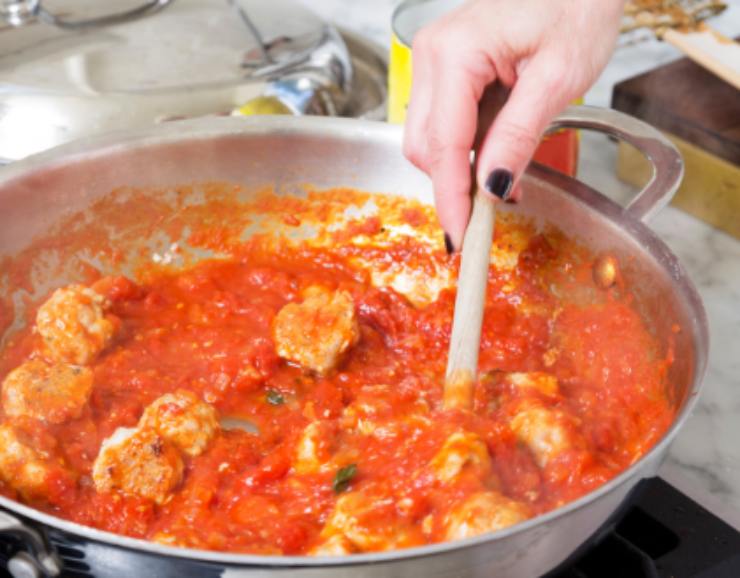 donna che mescola le polpette al sugo in una casseruola