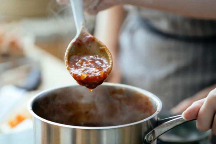 sugo di pomodoro che cuoce in pentola con mestolo