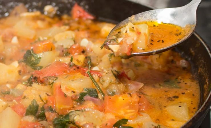 Verdure che cuociono in padella e un cucchiaio