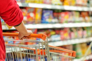 Persona che spinge carrello tra gli scaffali supermercato