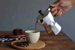 Persona che versa caffè in una tazzina con la moka