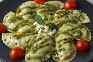 piatto con ravoli, pesto e pomodorini