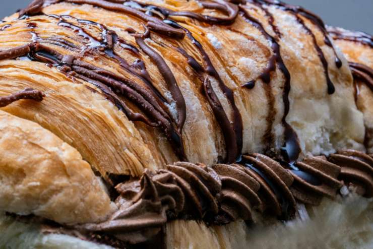 primo piano di cornetto sfogliato ripieno di crema al cioccolato