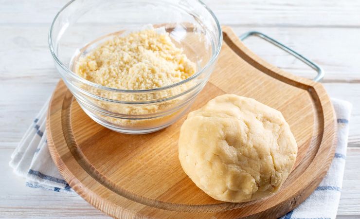 Panetto di pasta frolla sul tagliere con ciotola accanto
