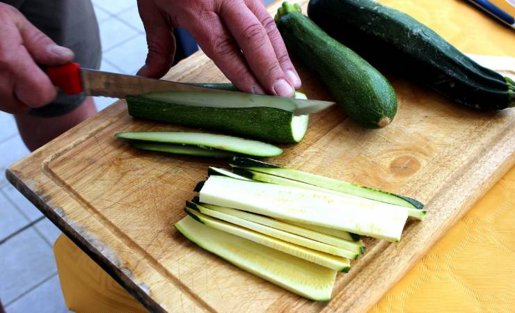 Persona che taglia le zucchine nel senso della lunghezza