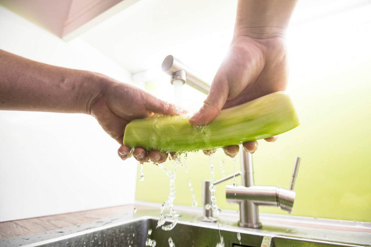Persona che lava zucchina sotto acqua corrente