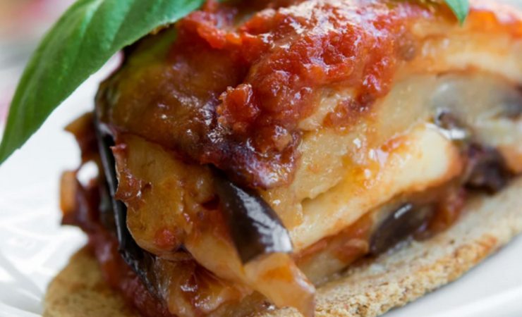 Porzione di pasticcio di melanzane con foglie di basilico