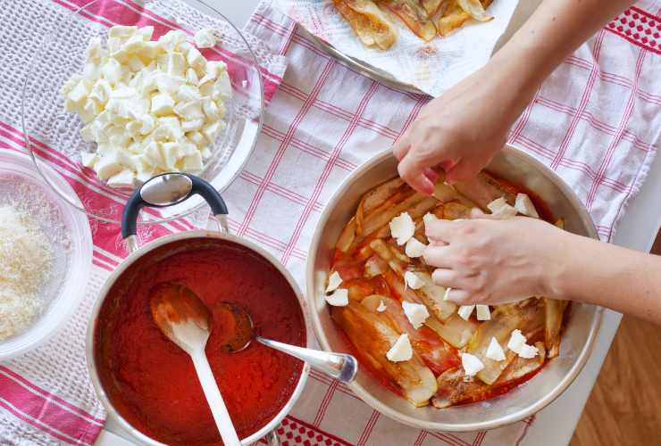 tavolo con pentola, sugo, mozzarella e parmigiano
