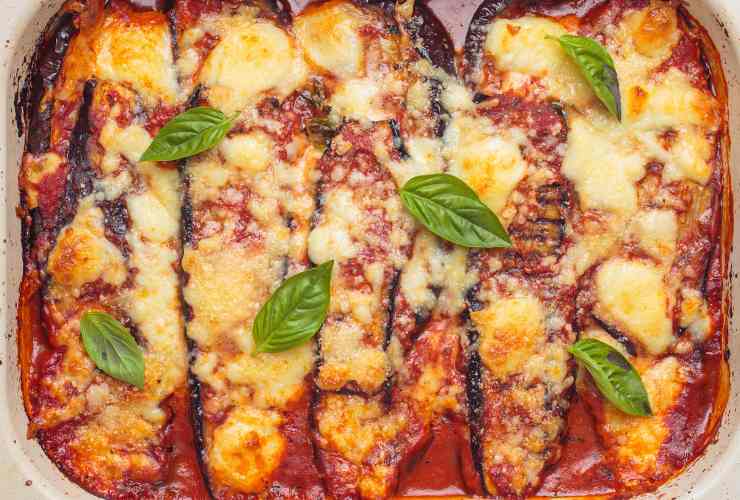 parmigiana di melanzane fumante in teglia con foglie di basilico