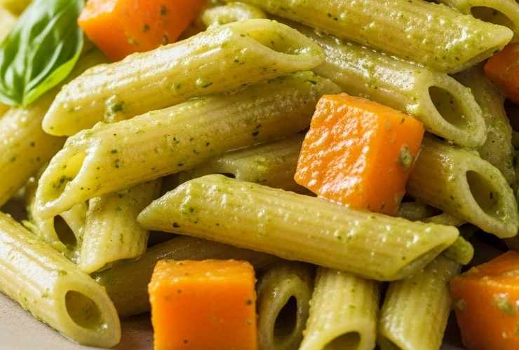 primo piano di pasta condita con pesto e pezzi di zucca