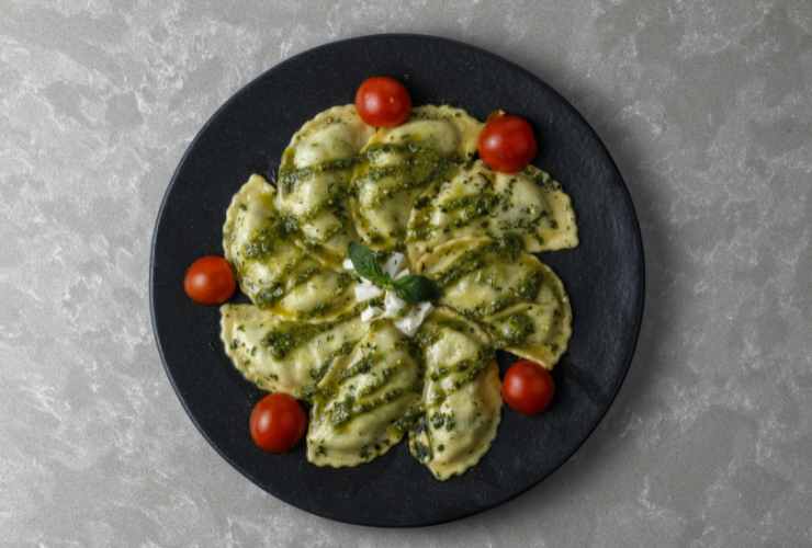 piatto con ravioli, pesto e pomodorini