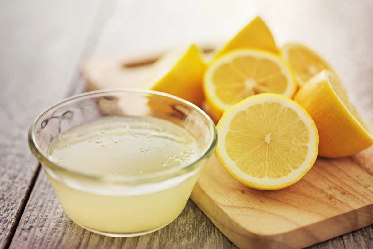 Succo di limone in una ciotola con limoni aperti accanto