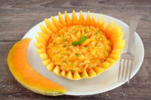 risotto al melone dentro mezzo melone e accanto una fetta di melone