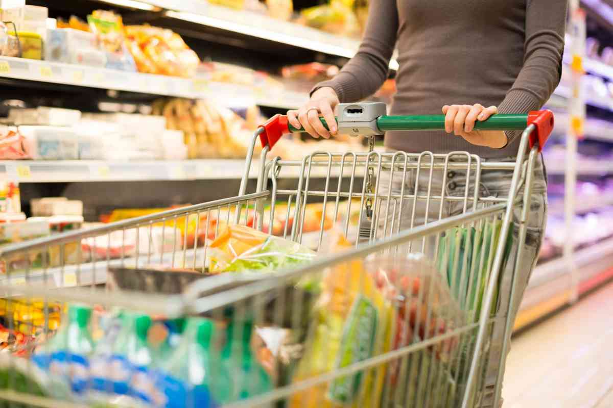 Donna che spinge carrello pieno nel supermercato