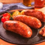tre salsicce su un piatto con accanto delle verdure