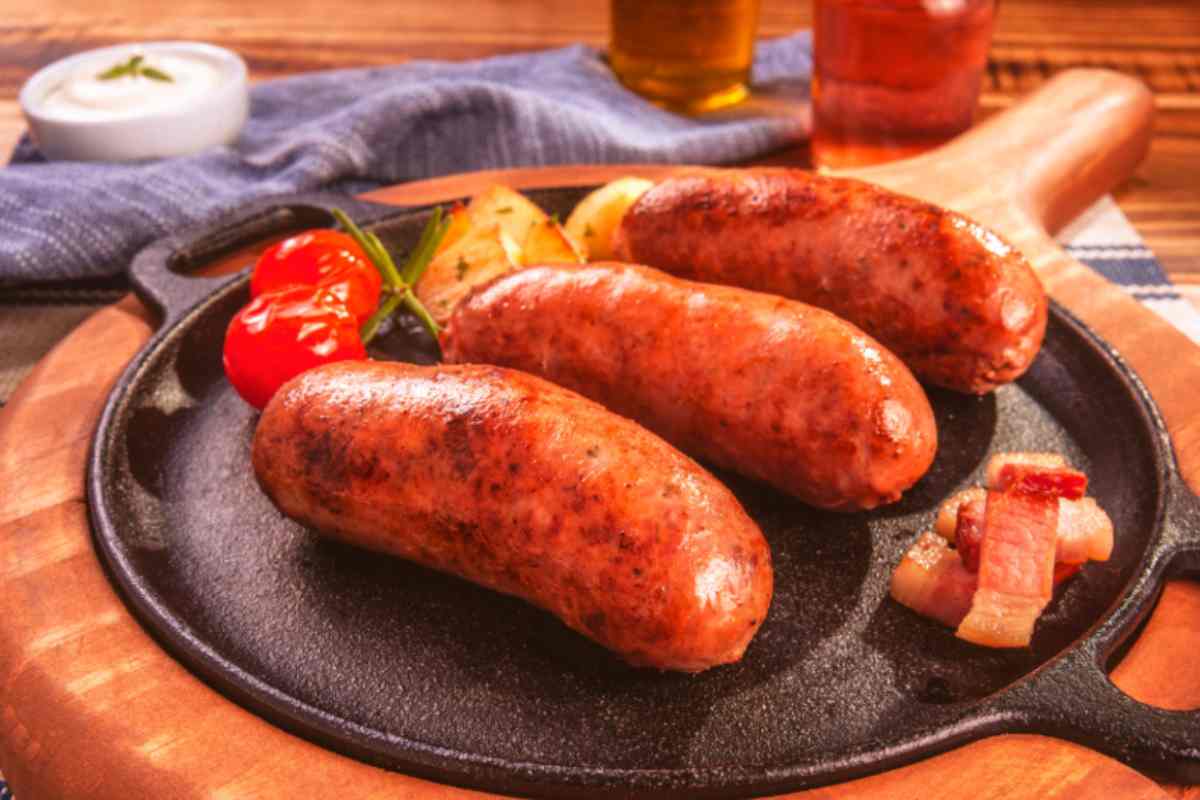 tre salsicce su un piatto con accanto delle verdure