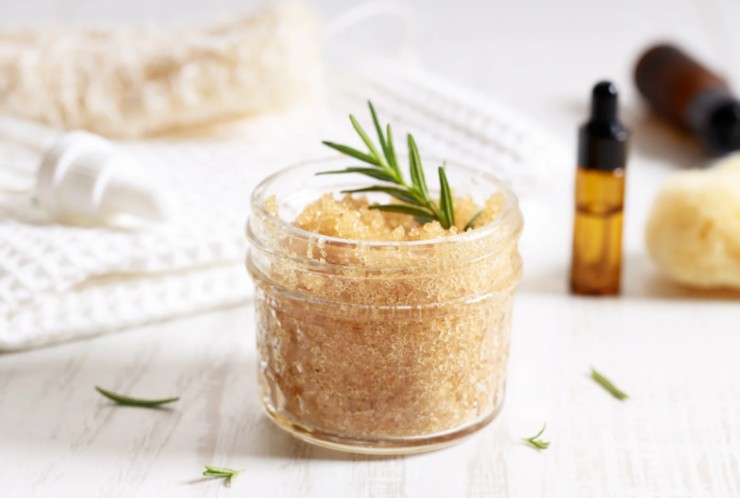 scrub con zucchero di canna e accanto dei bottiglini di olii essenziali