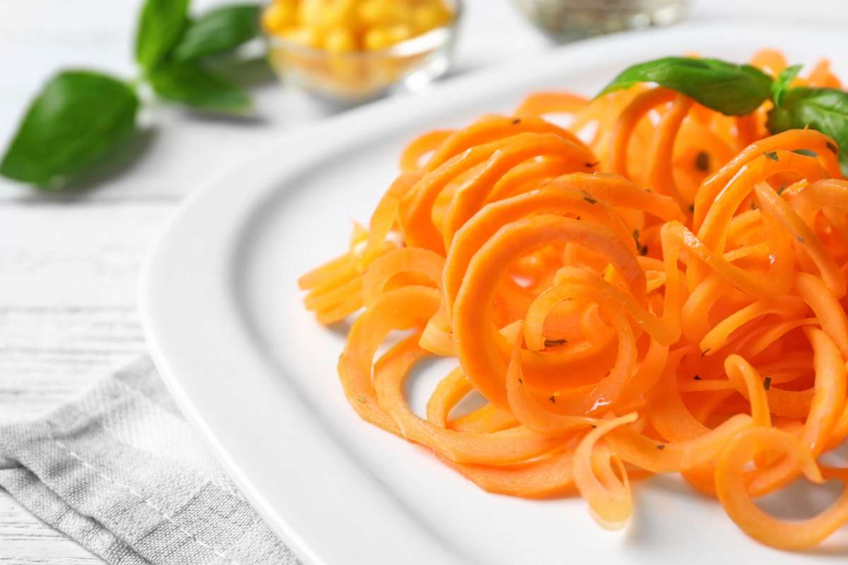 Piatto con spaghetti di carote e foglie di basilico