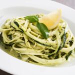 spaghetti di zucchine con sopra uno spicchio di limone e delle foglioline di basilico