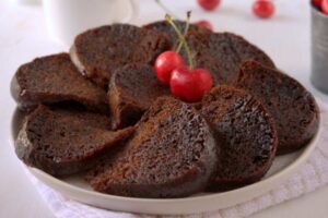 torta al cioccolato a fette su un piatto con sopra due ciliegie